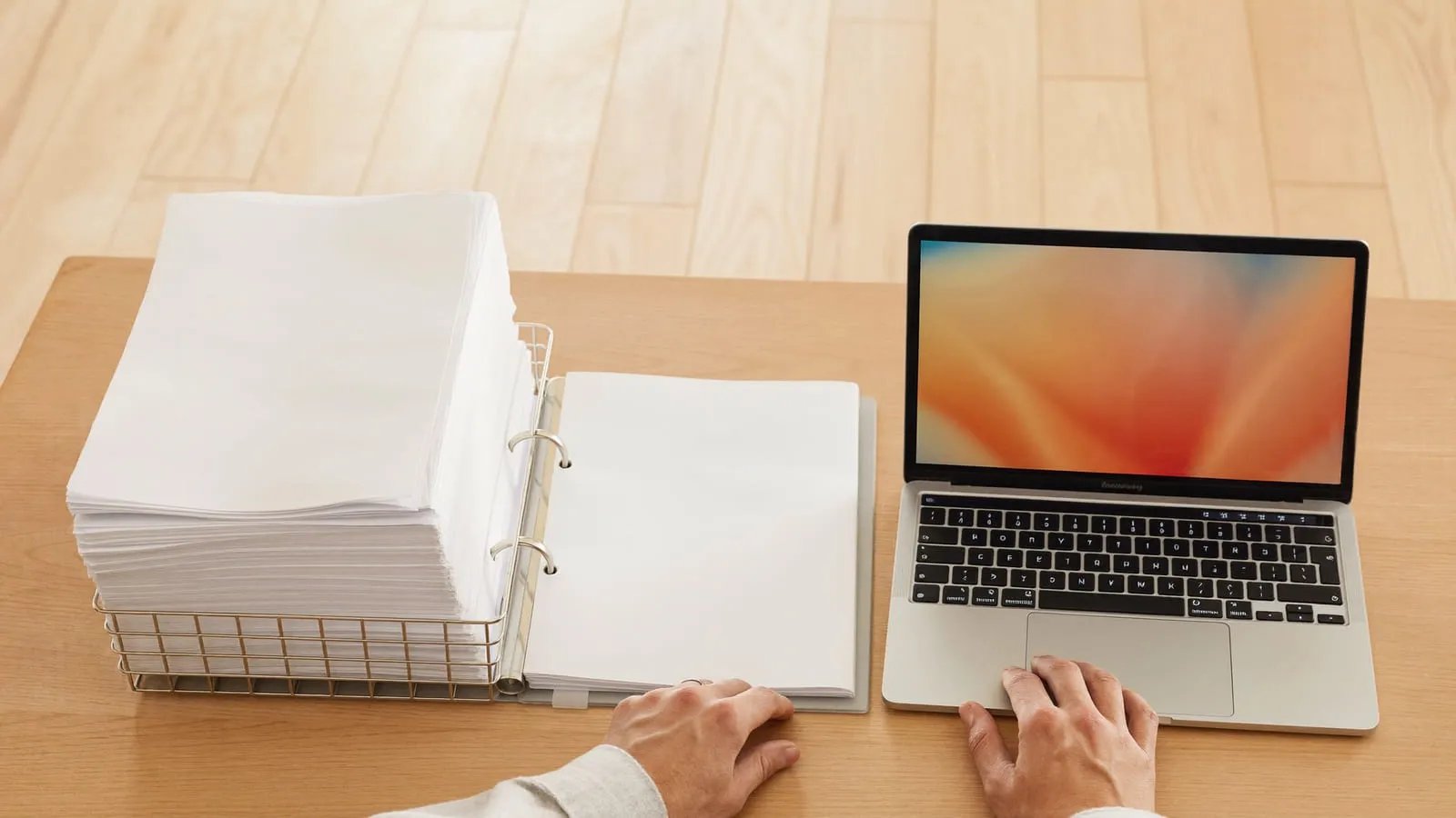 Schreibtisch mit einem hohen Stapel Papierrechnungen neben einem Notebook — Rechnungsbearbeitung vor und nach der Umstellung auf E-Rechnung